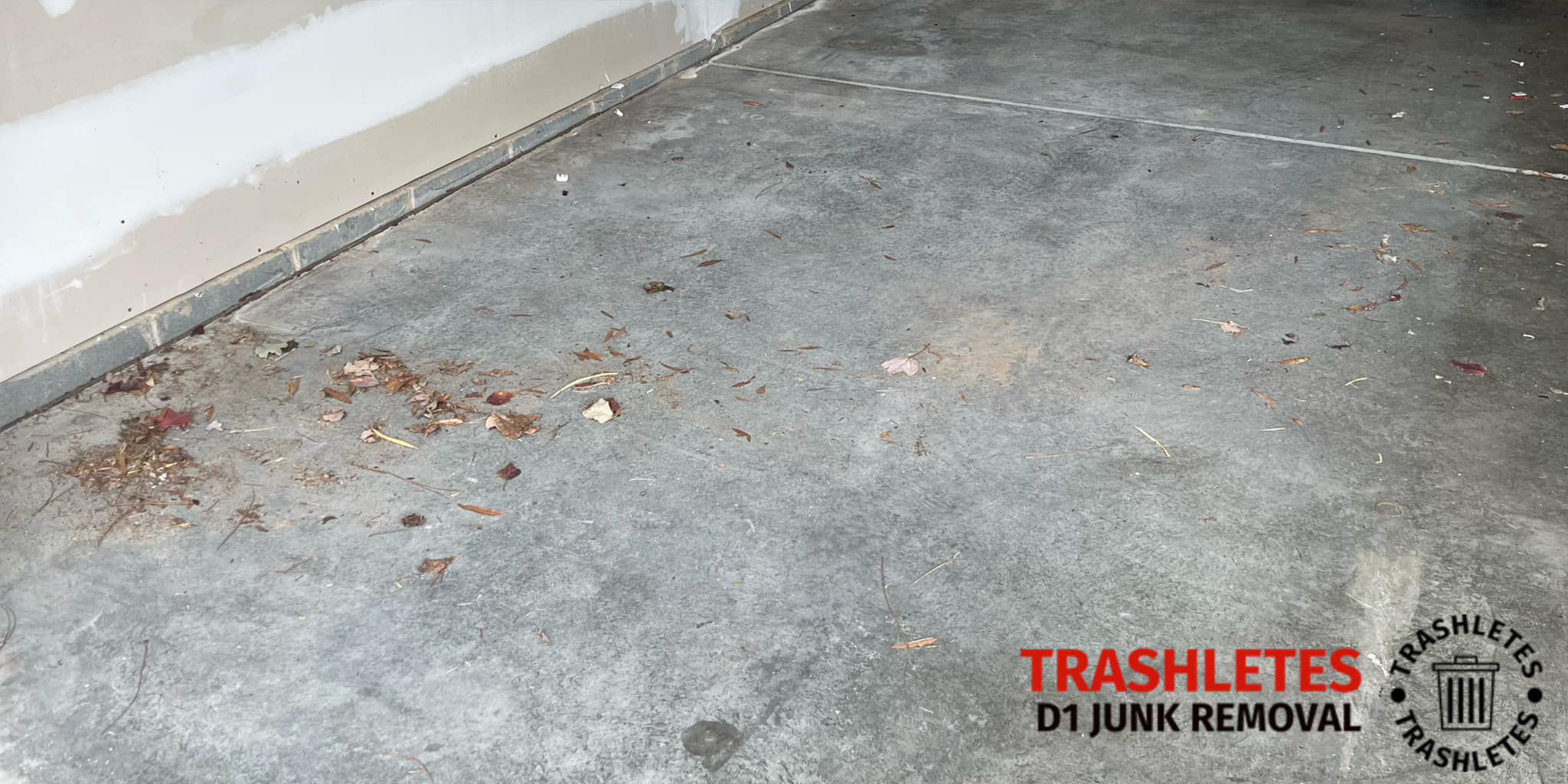 Empty garage space with a concrete floor scattered with leaves and debris. A logo and text in the lower right corner reads TRASHLETES D1 JUNK REMOVAL.